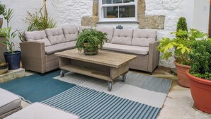 A cozy outdoor seating area with a sofa, a coffee table, and potted plants.