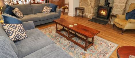 A cozy living room with a stone fireplace, a grey sofa set, and a wooden coffee table.