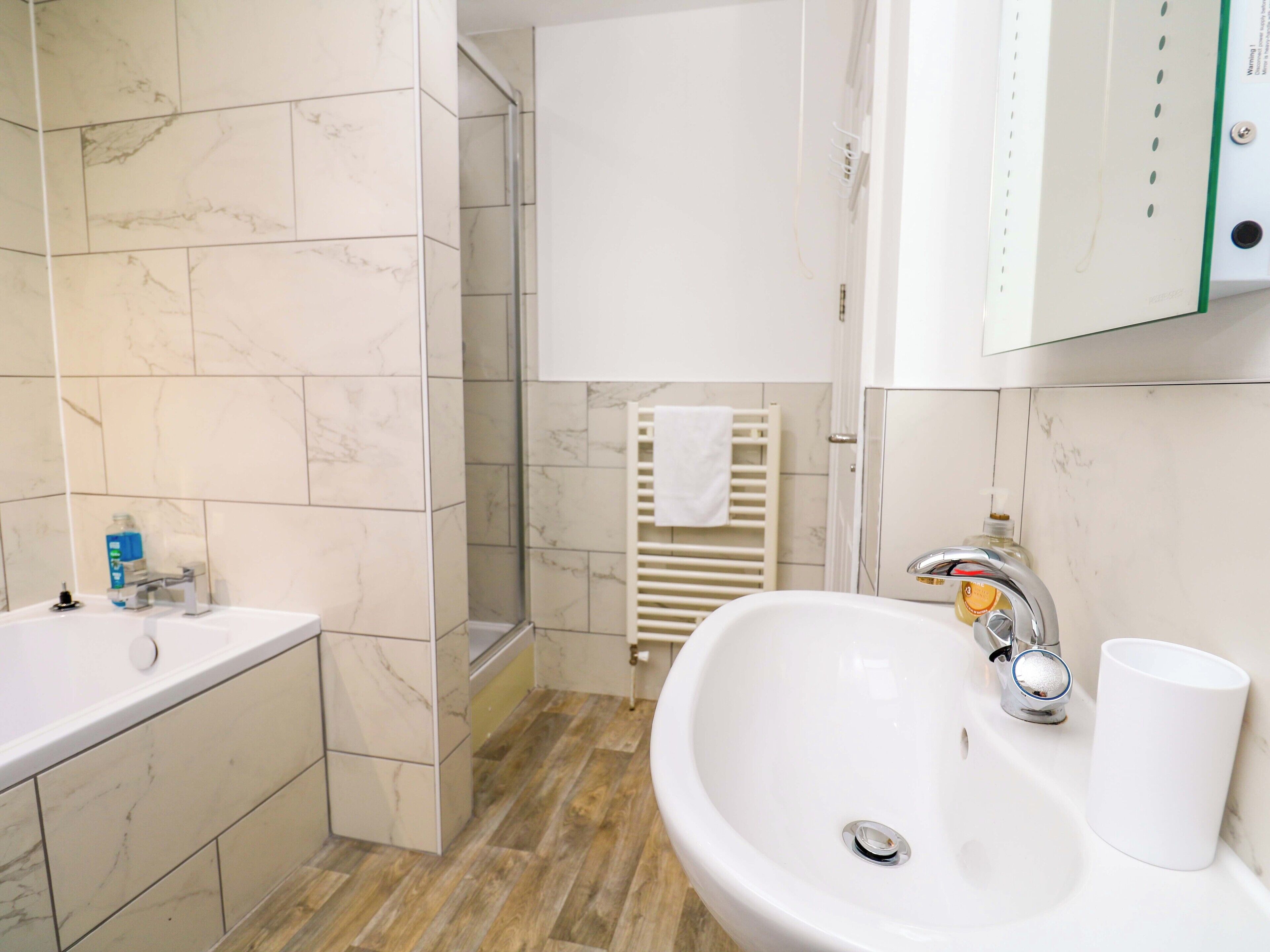 Une salle de bain avec un lavabo blanc, un miroir et un espace douche.