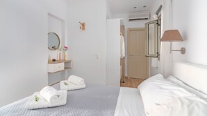 Quarto de hotel com cama, mesa de cabeceira com luminária, espelho e guarda-roupa.