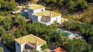 Uma villa com piscina, vários edifícios e paisagem verde exuberante.