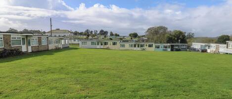 Un parque para caravanas con múltiples caravanas y un campo cubierto de césped.