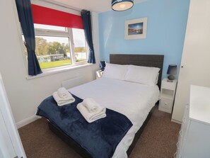 A neatly made bed with two towels, a bedside lamp, and a picture on the wall. - Culver View - Chalet 129 Sandown Bay Holiday Centre (Sandown)