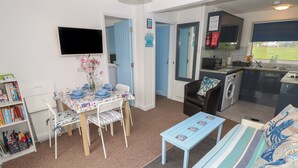 A compact living space with a dining area, a sofa, a small table, and a kitchenette.