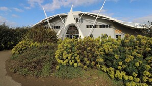 A modern building with a unique curved roof and a sign indicating it is a dinosaur museum.