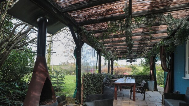 An outdoor patio with a brick oven, wooden table, and chairs. - Brook Cottage (Sturminster Newton)
