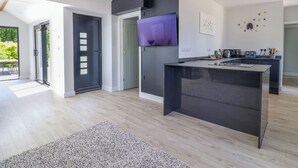 Una cucina moderna con isola centrale, televisione a schermo piatto e zona pranzo con tavolo e sedie.