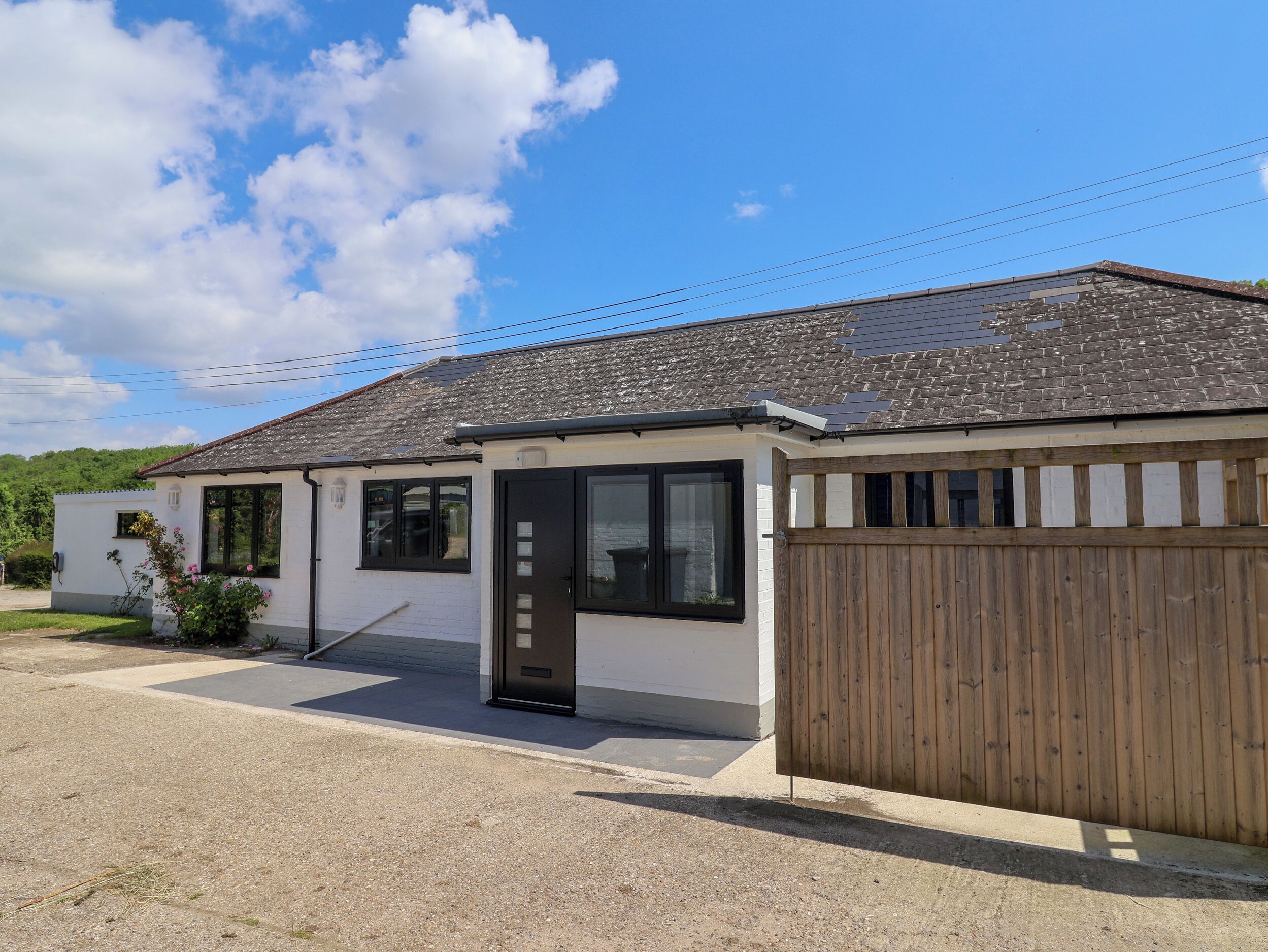 Une maison de plain-pied avec un toit en tuiles, une clôture en bois et une allée pavée.