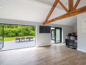 A spacious room with a large sliding glass door leading to an outdoor area with a wooden table and chairs. - Hartgrove Farm Bungalows (Axminster)