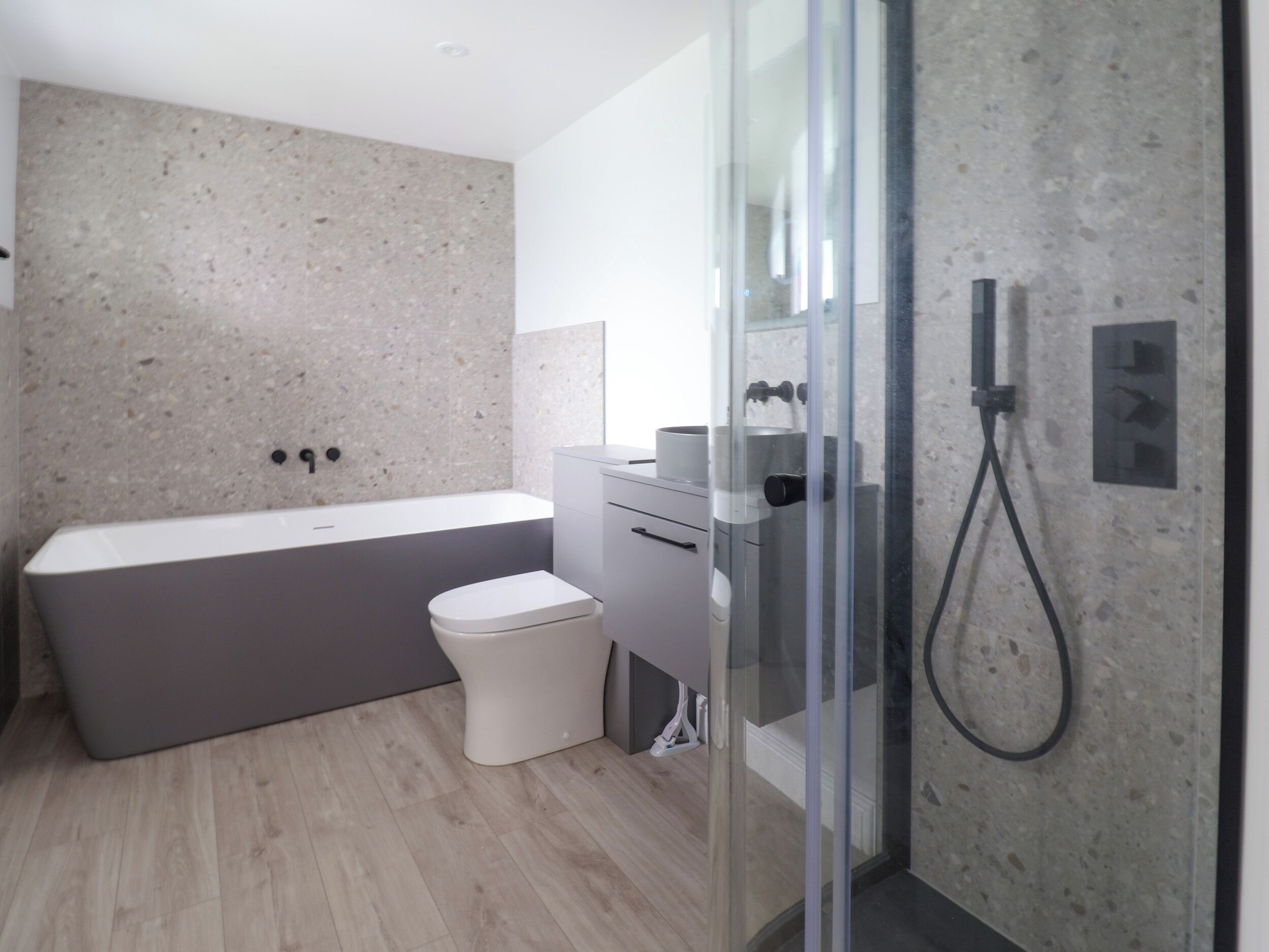Ein modernes Badezimmer mit einer freistehenden Badewanne, einer Toilette und einer in Glaswänden gefassten Duschkabine.