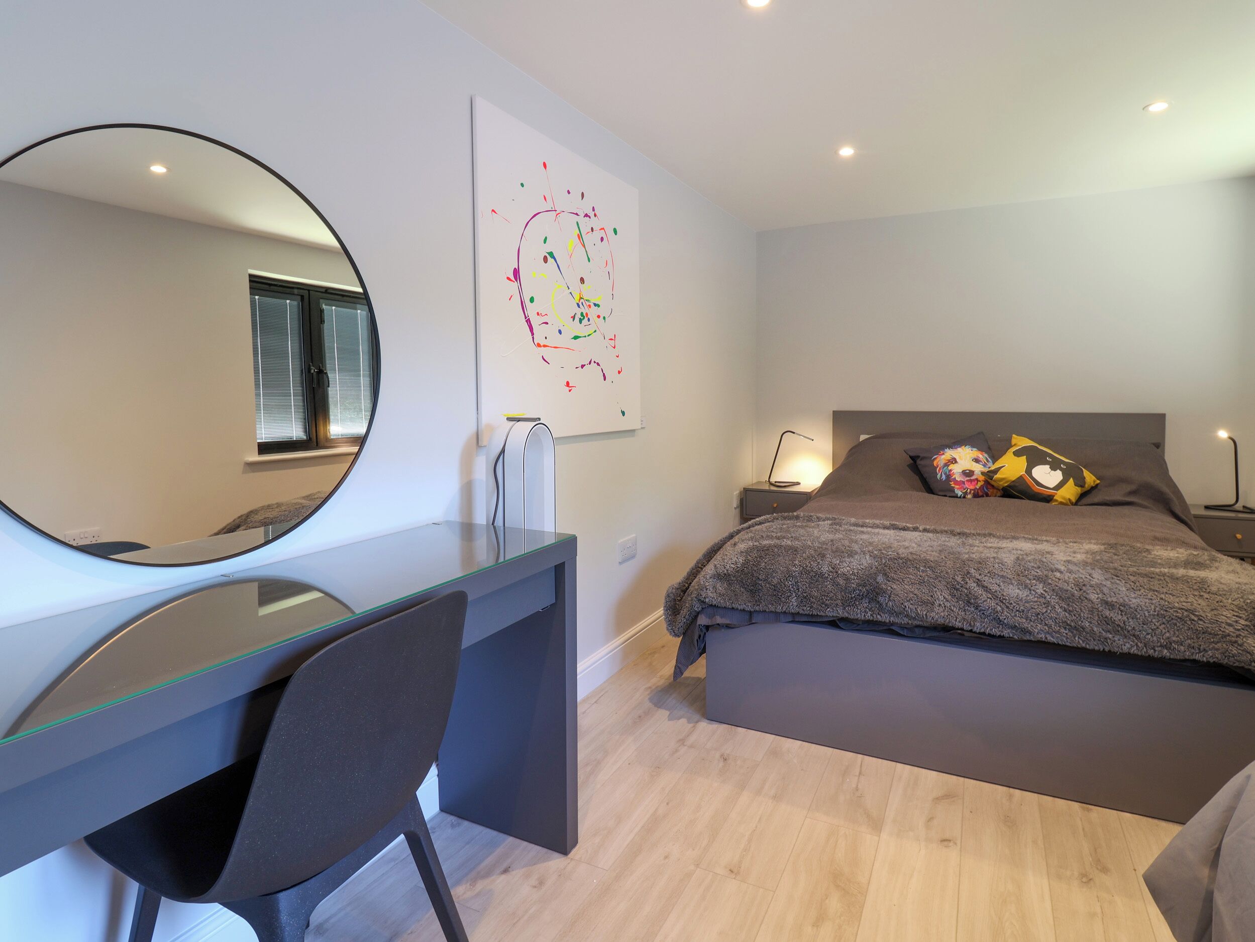 Un dormitorio moderno con cama, escritorio y silla.