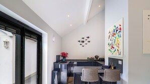 Una cucina moderna con isola centrale, sgabelli da bar e un quadro decorativo a tema pesce.