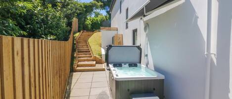 A spa area with a hot tub, wooden steps, and a white building.