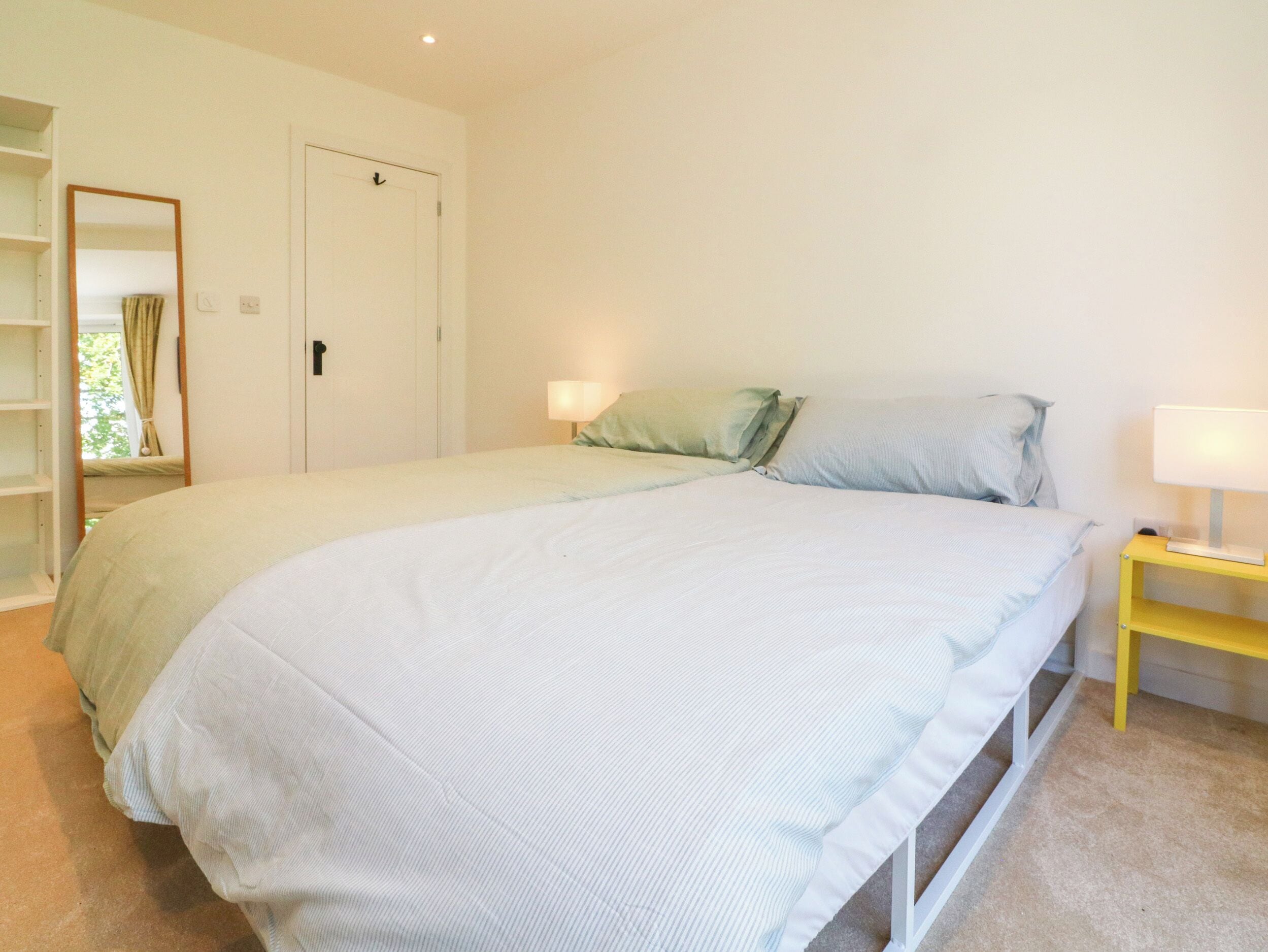 Une chambre à coucher avec un lit, une table de chevet avec une lampe, une armoire et un miroir.
