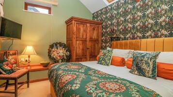 Un dormitorio con una cama grande, un armario de madera, un televisor en la pared y un tragaluz.