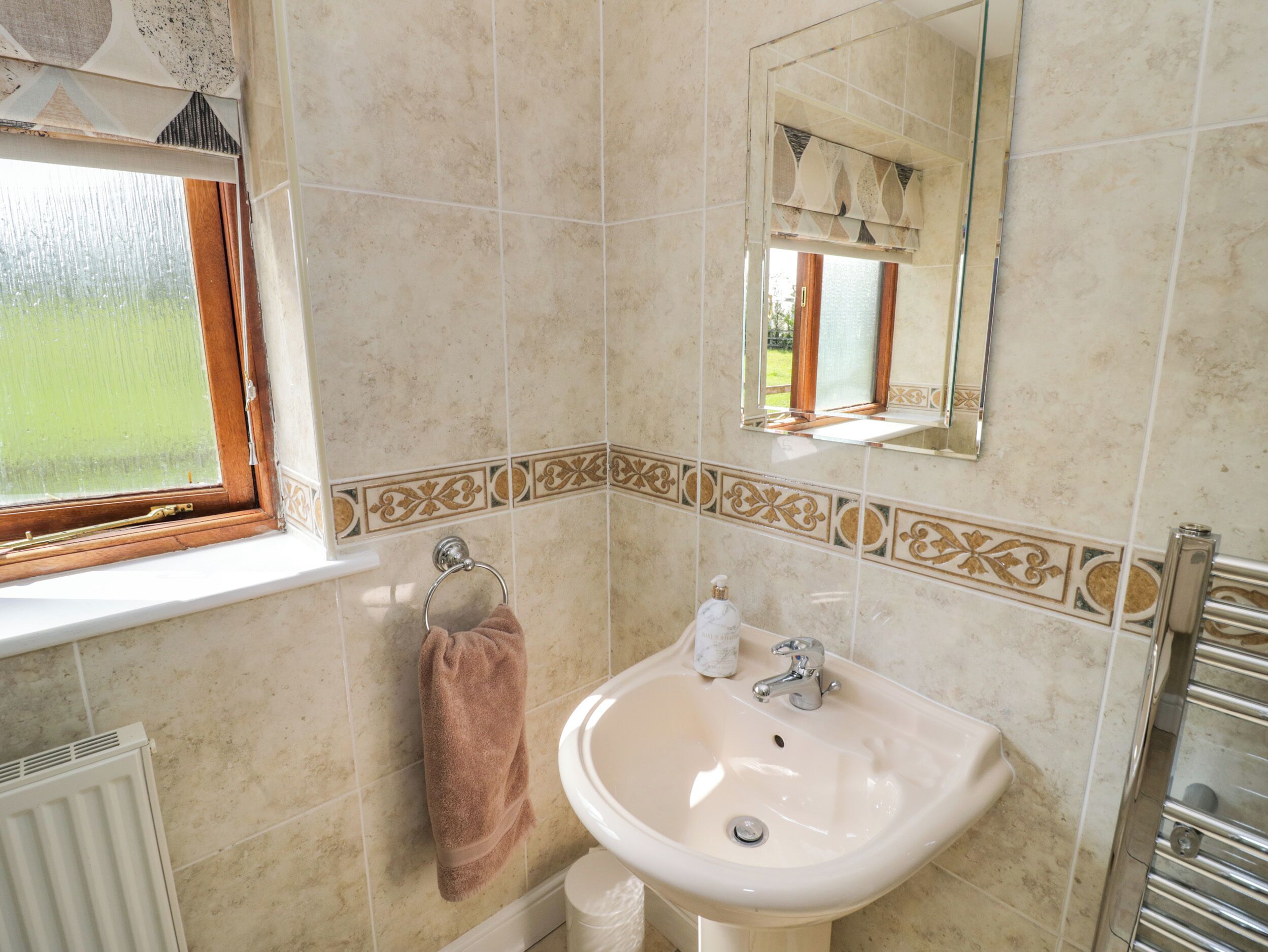 A bathroom with a sink, towel rack, and a window.