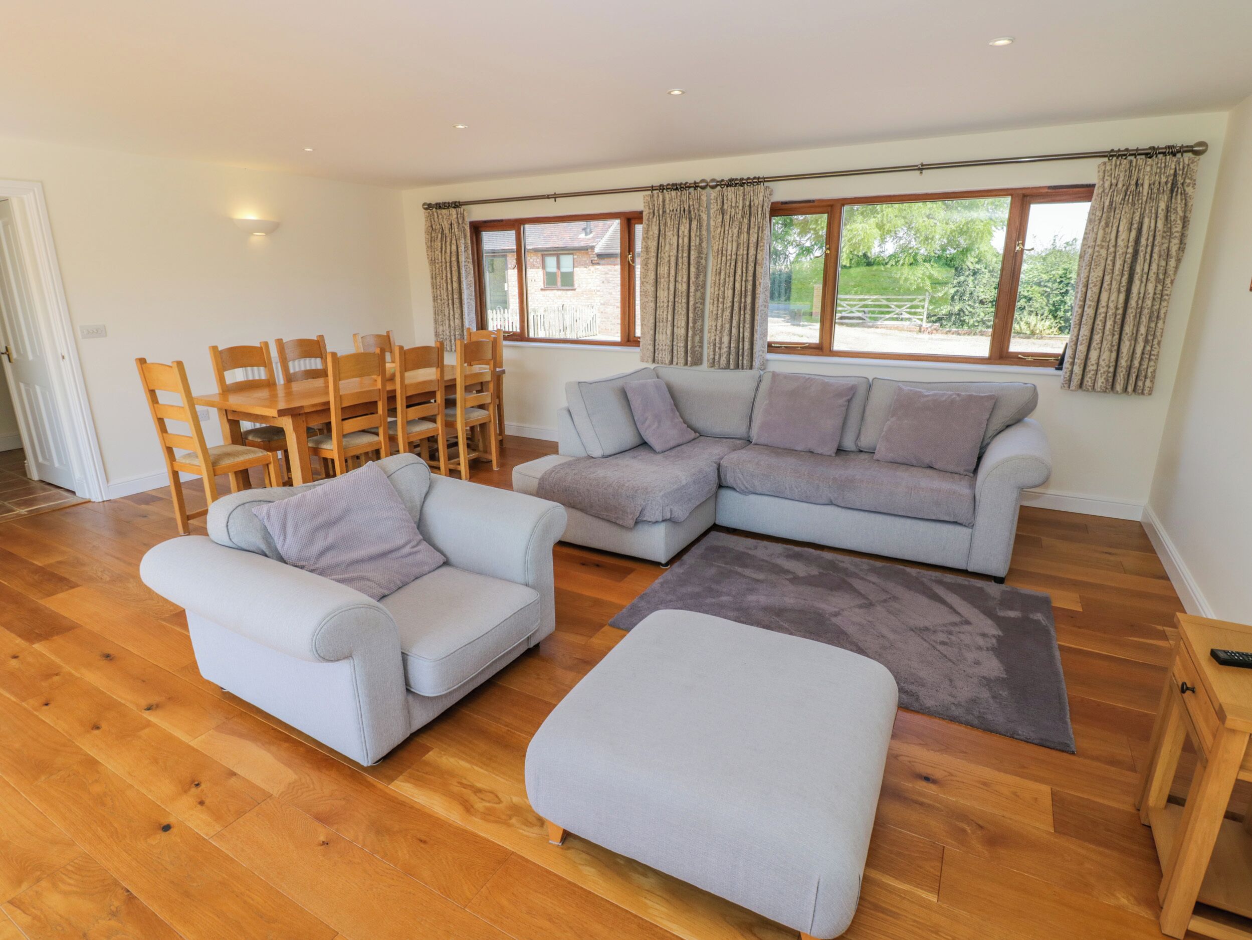 Ein geräumiges Wohnzimmer mit grauem Sofa, passendem Sessel und einem Holzessttisch mit Stühlen.
