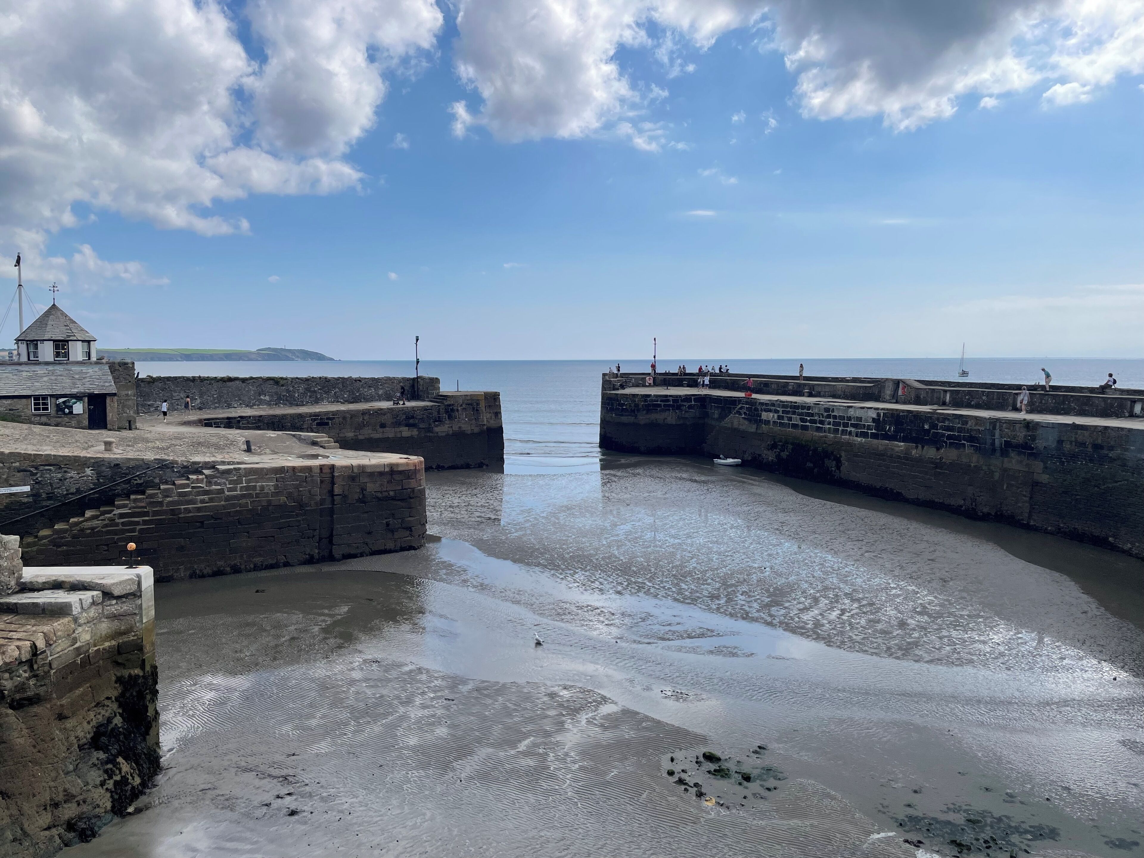 Une fortification côtière comprenant un phare, un petit bâtiment et une jetée s’avançant dans la mer.