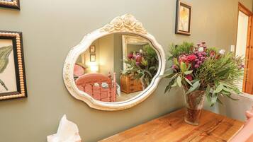 A wooden table with a mirror, a vase with flowers, and a tissue box.