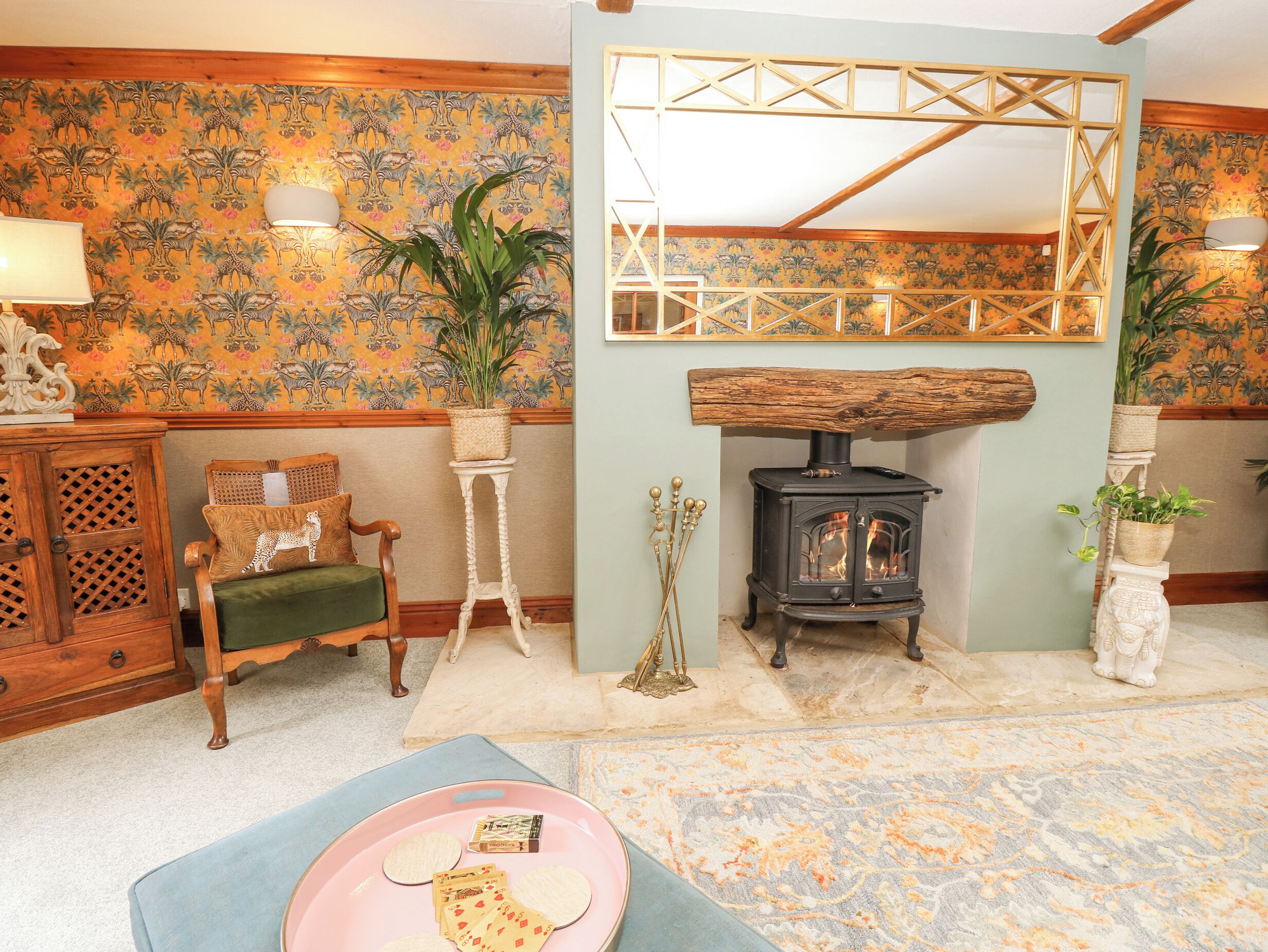 A cozy room with a wooden chair, a small table with a plant, a fireplace, and a patterned wallpaper.