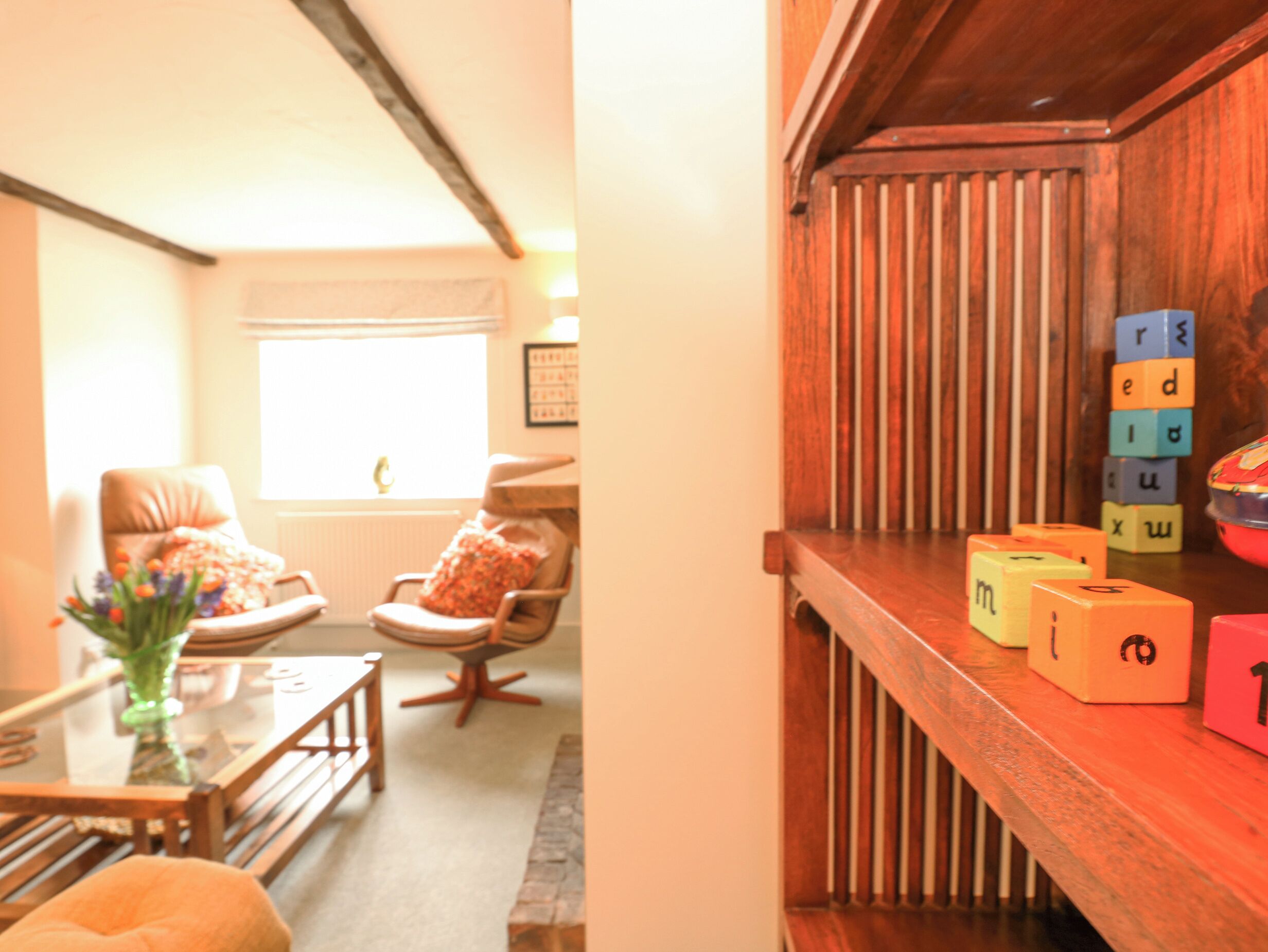 A cozy living room with a wooden coffee table, two chairs, and a window with blinds.