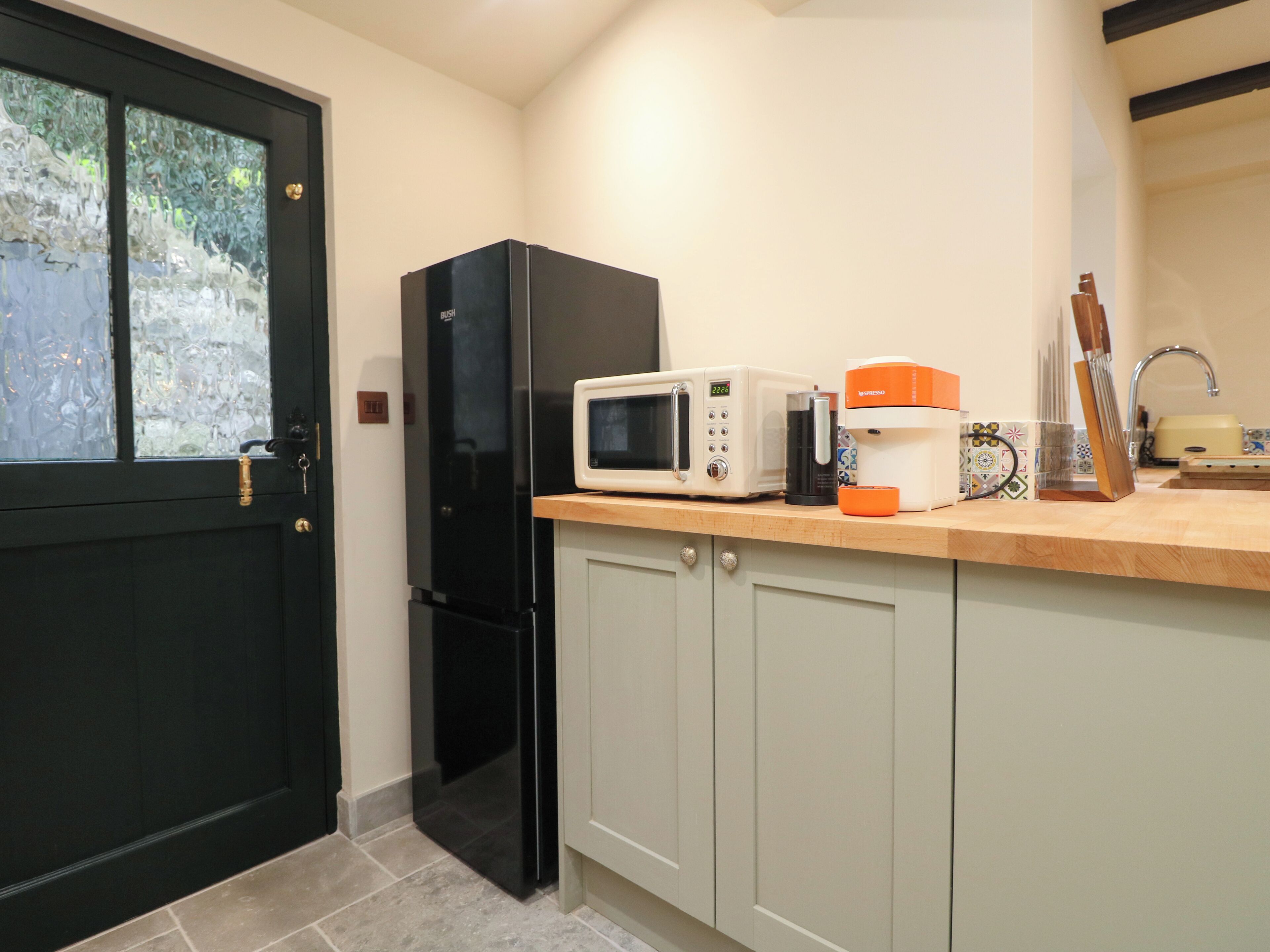 A kitchen with a black refrigerator, a microwave, and a coffee maker on the counter.
