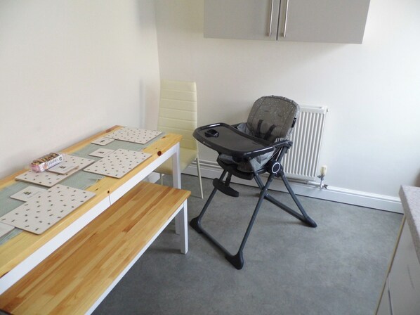 A room with a wooden table, a high chair, and a radiator.