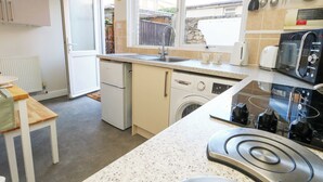 Een kleine keuken met een wasmachine, een fornuis, een magnetron en een broodrooster.