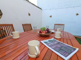 Una mesa de madera con un cuenco de fruta, dos tazas y un menú.