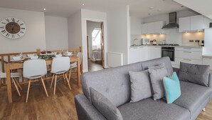 Un appartement moderne comprenant un coin repas, un canapé gris et une cuisine.