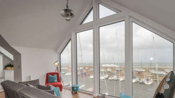 Un salon moderne doté d’une grande fenêtre donnant sur un port de plaisance.