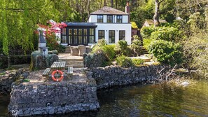 A house with a stone bridge over water, surrounded by greenery. - The Sheiling (Leek)