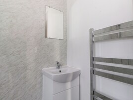 Un baño con un lavabo blanco, un espejo y un perchero para toallas.