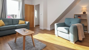 A modern living room with a sofa, armchair, and a small table. - 2 South Street (Wigton)