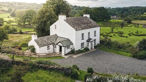 Une maison blanche avec une allée en gravier et un petit bâtiment annexe.