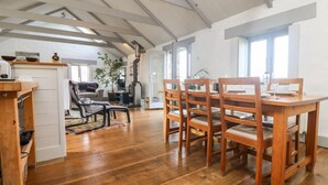 A spacious living area with a wooden dining table and chairs, a sofa, and a fireplace.