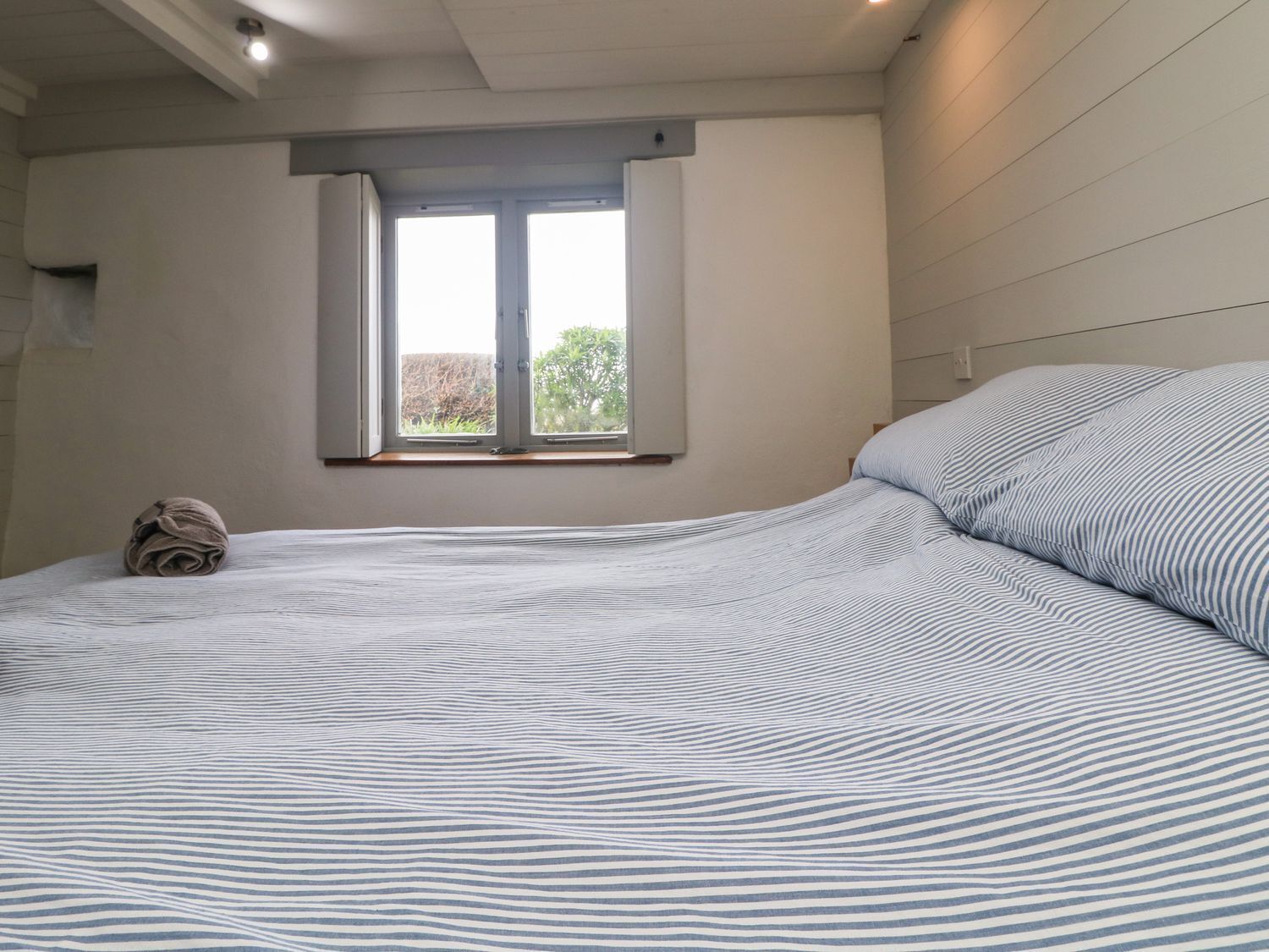 A bedroom with a bed, a window, and a towel on the floor.