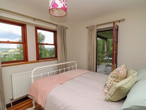 A bedroom with a bed, a window, a radiator, and a view of the outdoors. - Oak Apple Cottage (Presteigne)