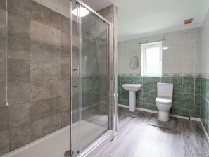 Une salle de bain avec une douche à parois de verre, un lavabo sur colonne et des toilettes.