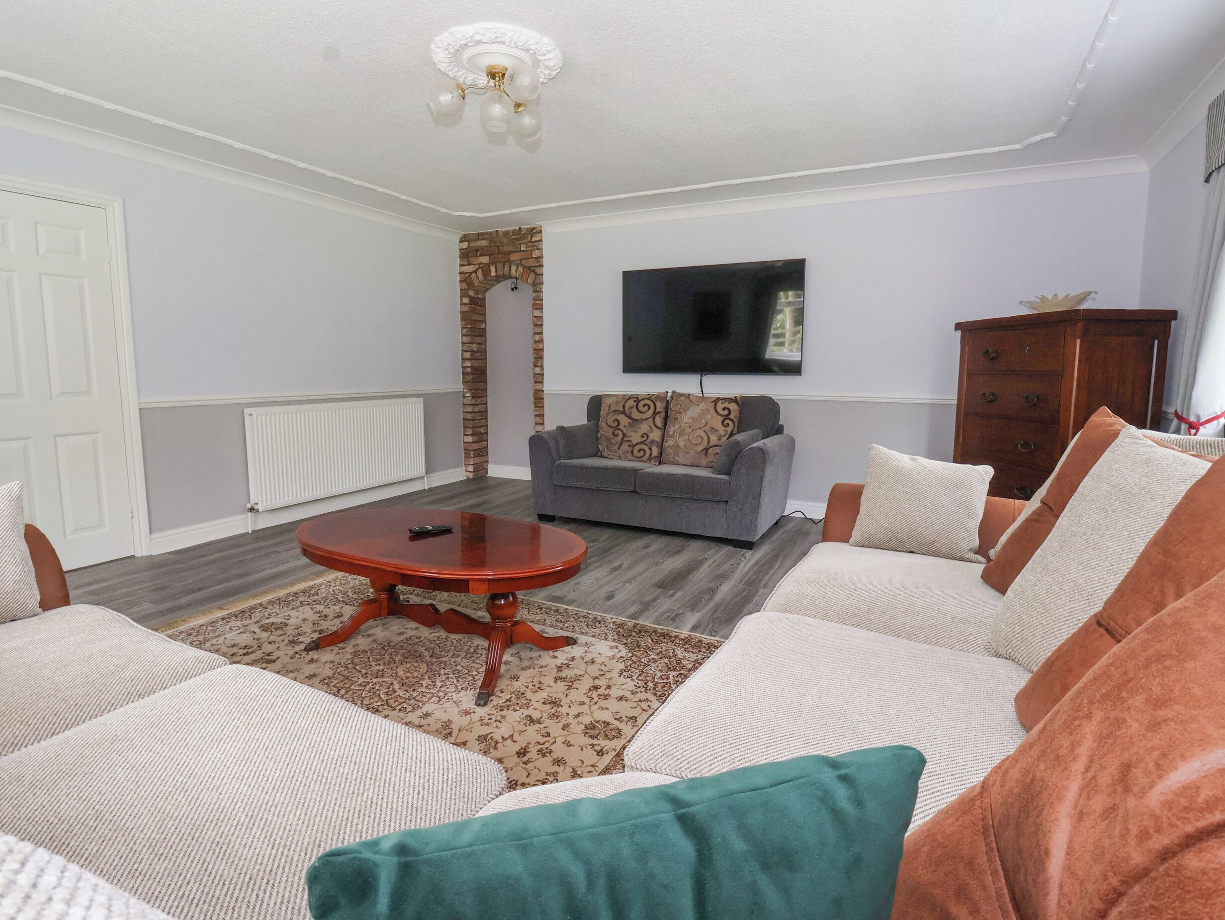 A living room with a grey sofa, a wooden coffee table, and a television mounted on the wall.