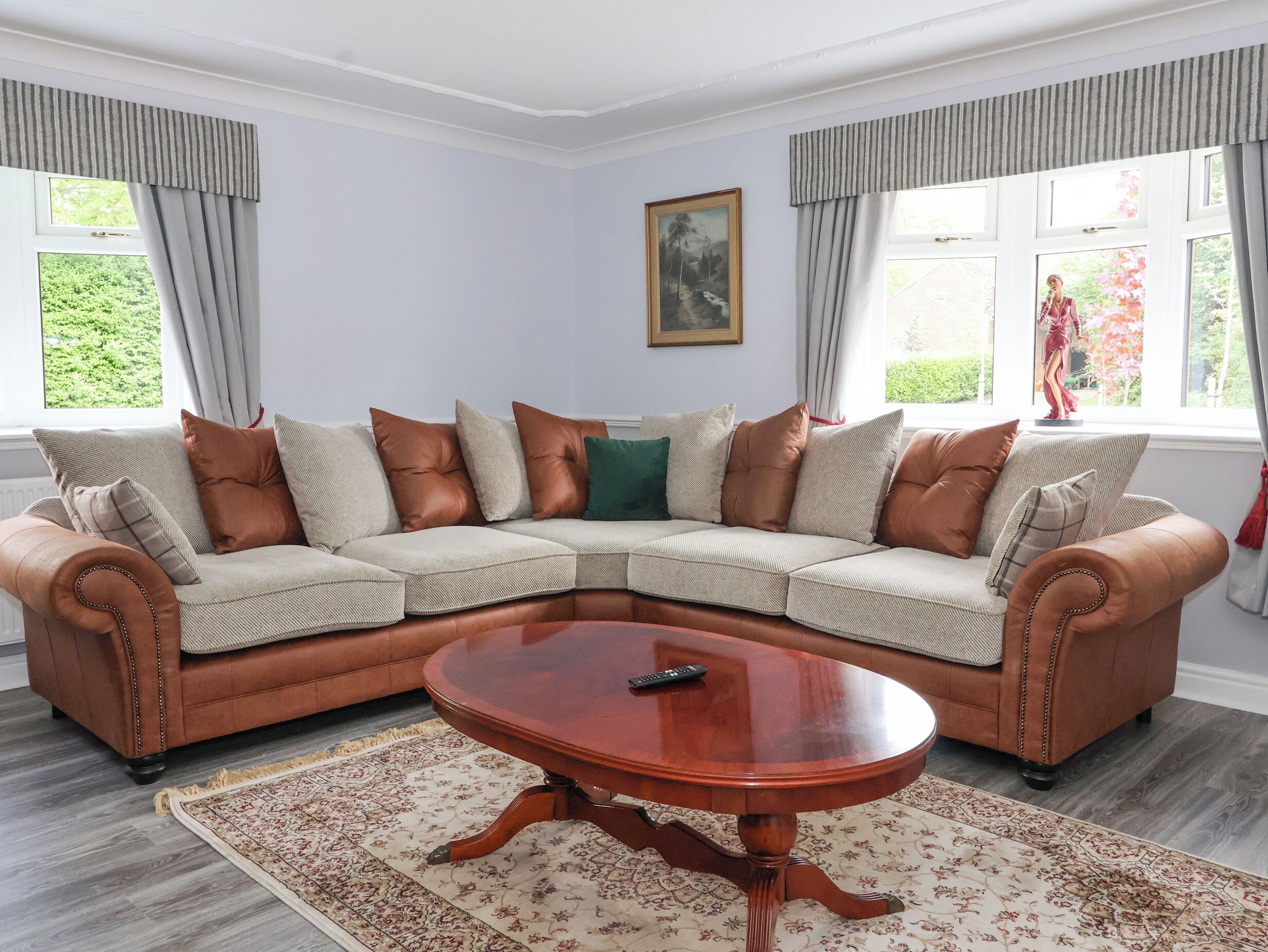 A living room with a beige sectional sofa, a wooden coffee table, and a patterned rug.