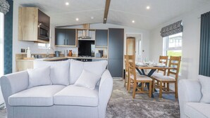 Una sala de estar moderna con un sofá gris, una mesa de centro de madera y un comedor con sillas y mesa de madera.