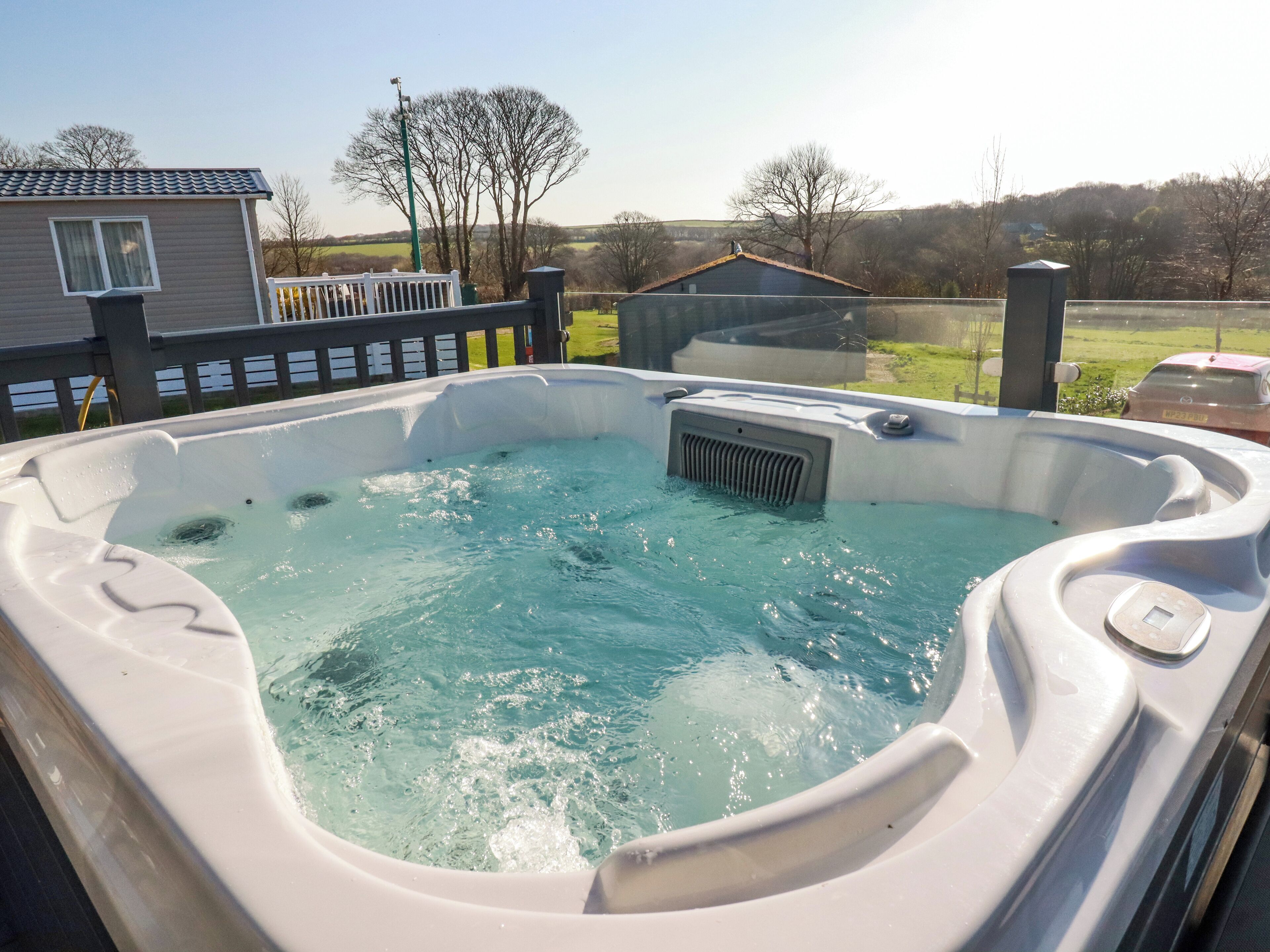 A hot tub with a view of a house and trees in the background.