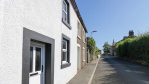Una calle estrecha flanqueada por casas de dos pisos con paredes blancas y detalles oscuros.