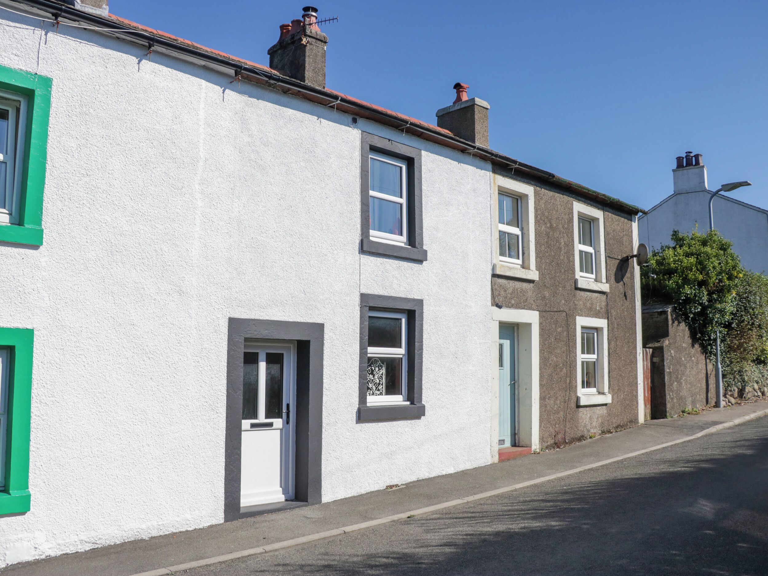 A row of terraced houses with white walls and green window frames.