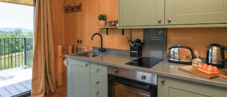 A kitchen with wooden cabinets, a sink, a toaster, and a view of the outdoors.