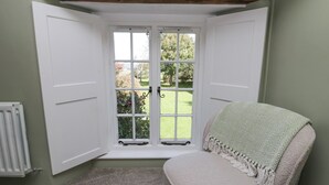 A room with a bay window, a radiator, and a chair with a blanket. - High Winder House (Penrith)
