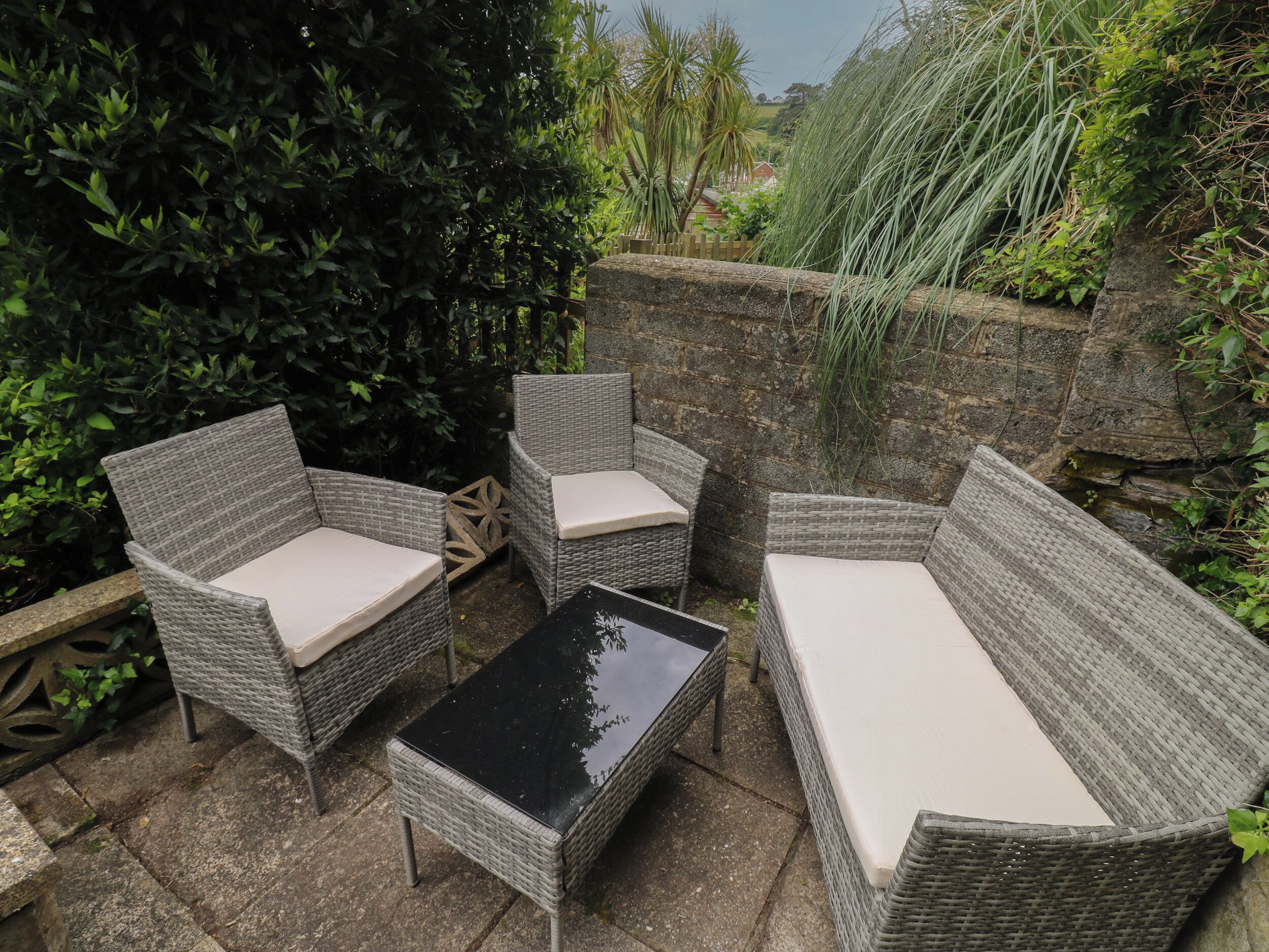 An outdoor seating area with wicker furniture and a black table.