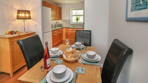 A dining area with a wooden table set for four, including plates, bowls, wine glasses, and bread. - The Chase - 30 Ayr Avenue (Catterick Garrison)