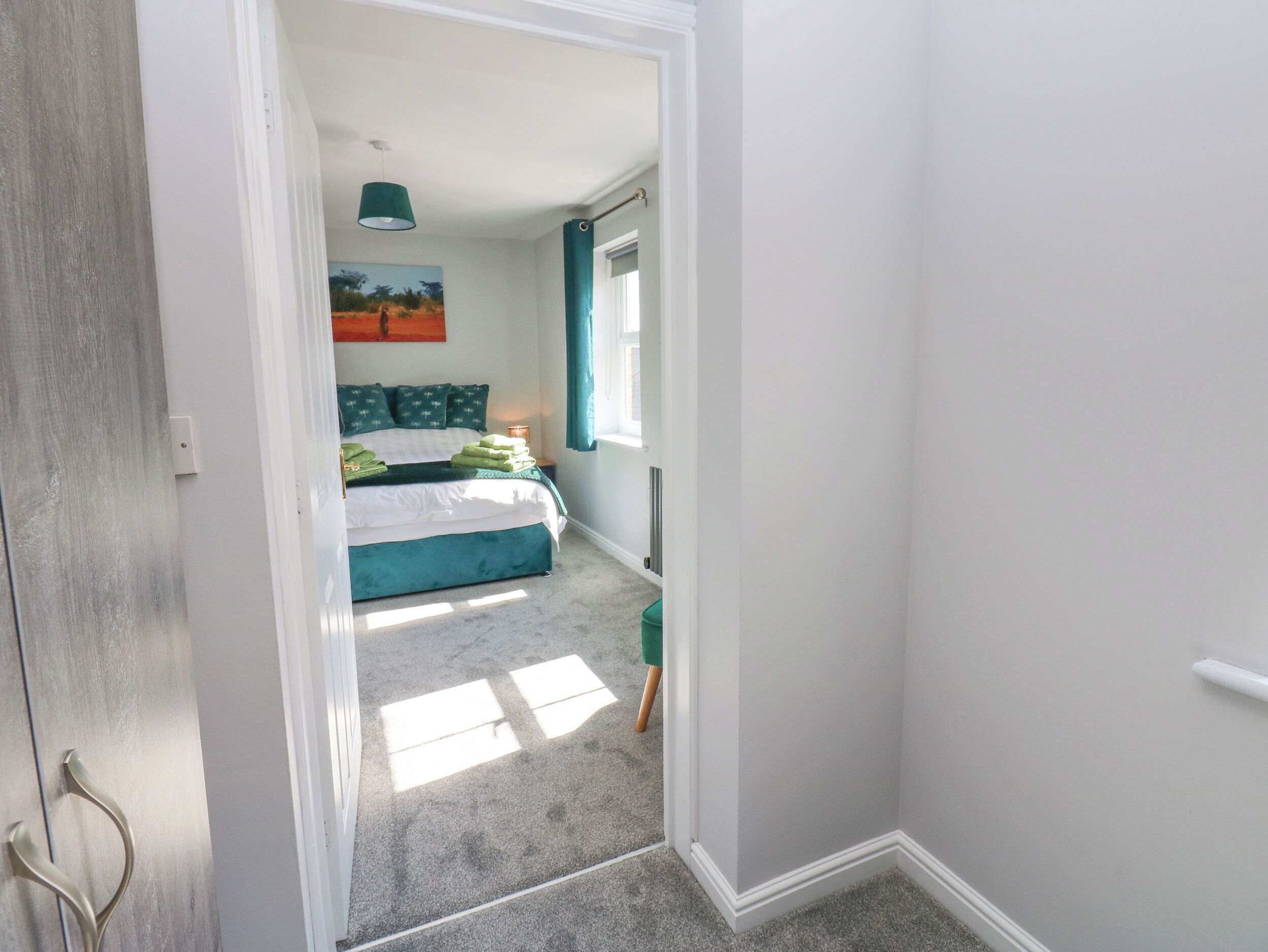 A bedroom with a bed, a nightstand, a lamp, and a painting on the wall.